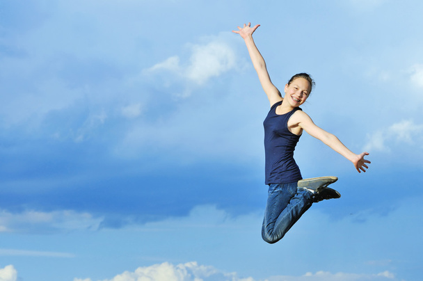 beautiful girl in gymnastic jump against blue sky - Photo, Image