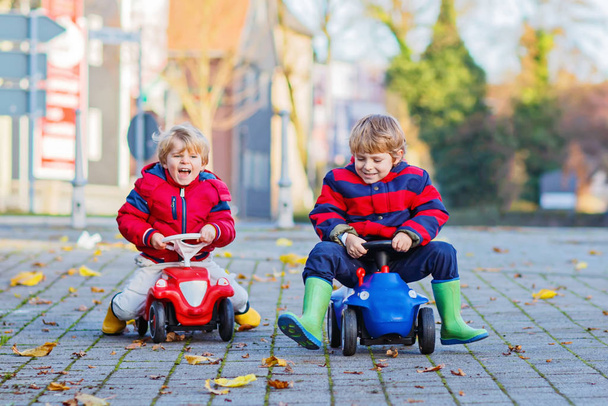 Dos niños jugando con coches de juguete, al aire libre
 - Foto, imagen