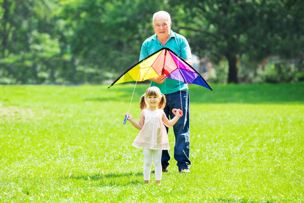 Granddaughter and Grandfather playing with Flying Kite  - Photo, image