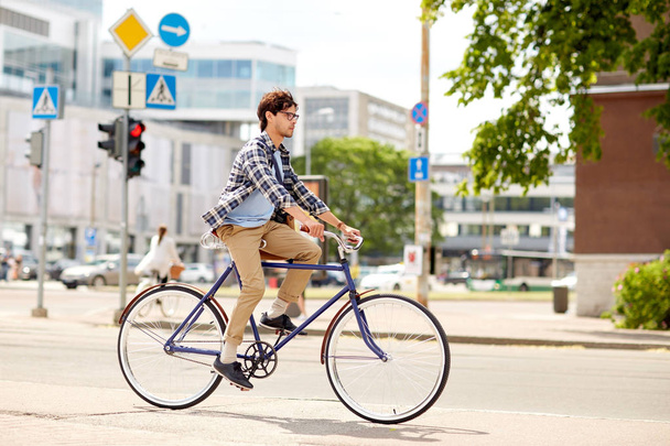young hipster man with bag riding fixed gear bike - Zdjęcie, obraz