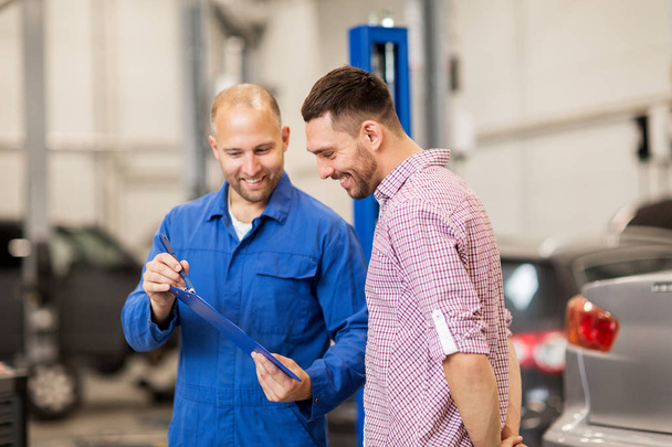 auto mechanic with clipboard and man at car shop - Foto, immagini