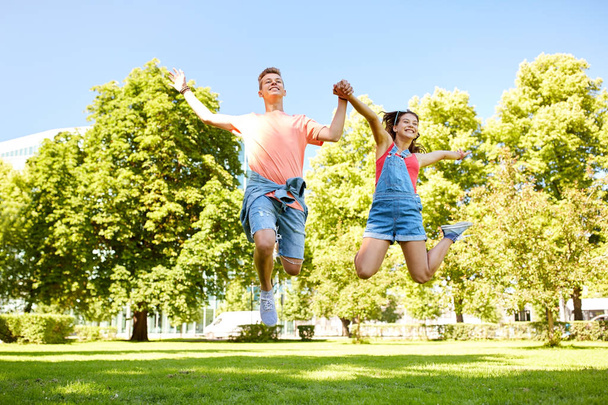 happy teenage couple jumping at summer park - Foto, afbeelding