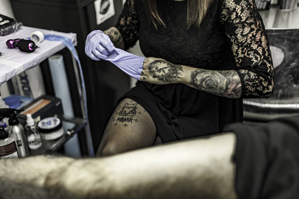 Close up woman hand with latex glove, tattooing in tattoo studio - Foto, Imagen