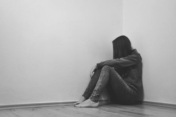Verdrietig meisje ondergedoken in hoek - Foto, afbeelding