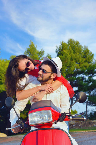 Beautiful young couple riding on a scooter - Foto, imagen