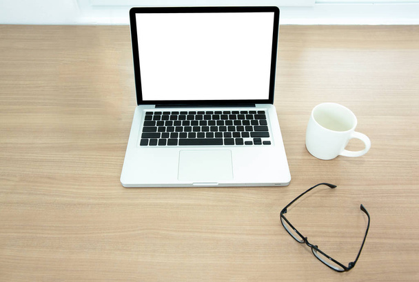 Un bureau avec tasse à café, verre et ordinateur avec écran balnk et clavier vierge sur table en bois
 - Photo, image