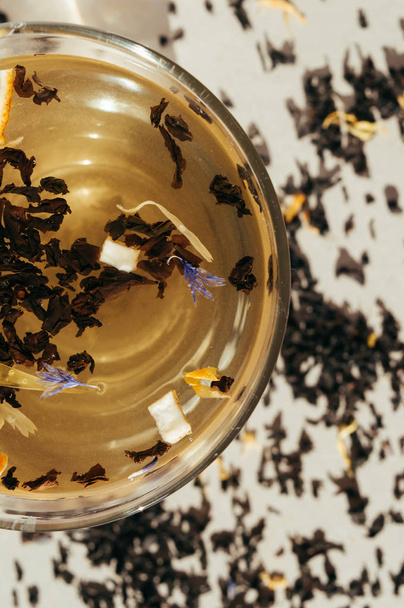 Чорний чай з блакитними квітами, апельсинова шкірка і пелюстки в транспа
 - Фото, зображення