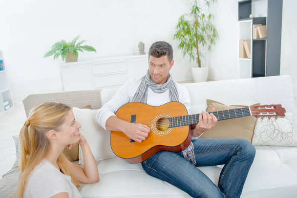 Man playing guitar to lady - Фото, изображение