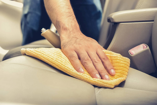 A man cleaning leather car seat with microfiber cloth  - Photo, Image