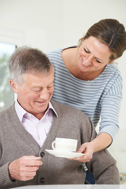 Adult Daughter Bringing Senior Father Hot Drink At Home - Photo, Image