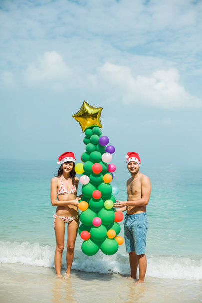 casal segurando balão árvore na praia
 - Foto, Imagem