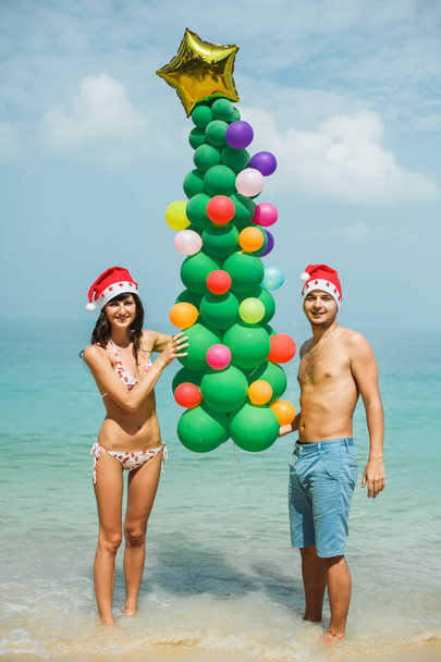 pareja sosteniendo globo árbol en playa
 - Foto, imagen