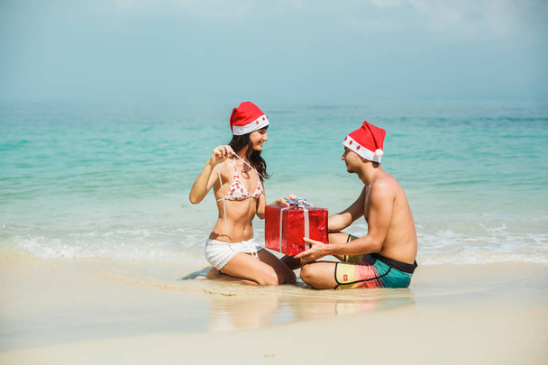 пара сидить з подарунковою коробкою на пляжі
 - Фото, зображення