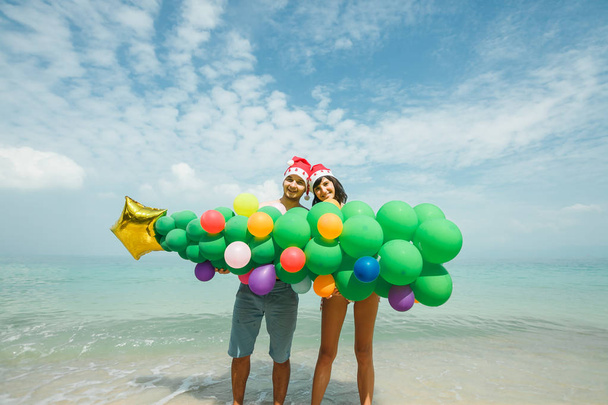 pareja sosteniendo globo árbol en playa
 - Foto, imagen