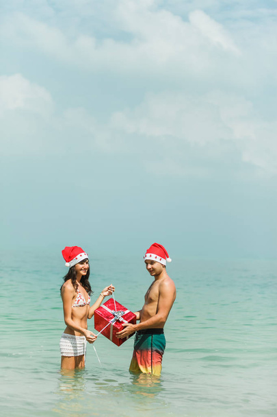 pareja de pie con caja de regalo en agua
 - Foto, imagen