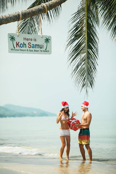 pareja de pie con caja de regalo en la playa
 - Foto, imagen