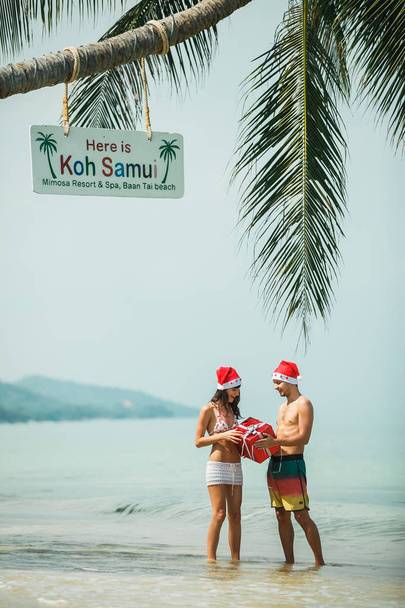 pareja de pie con caja de regalo en la playa
 - Foto, Imagen