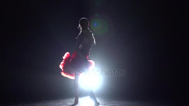 Chica bailando rumba sobre un fondo oscuro con iluminador de luz. Movimiento lento
 - Metraje, vídeo