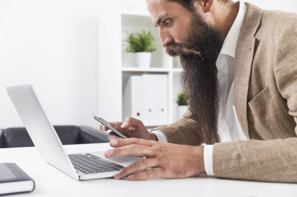 Side view of businessman with long beard looking at his cell pho - Foto, Imagem
