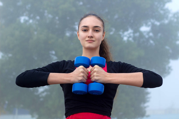 Fiatal sportos lány gyakorlatok során képzés workou dumbells - Fotó, kép