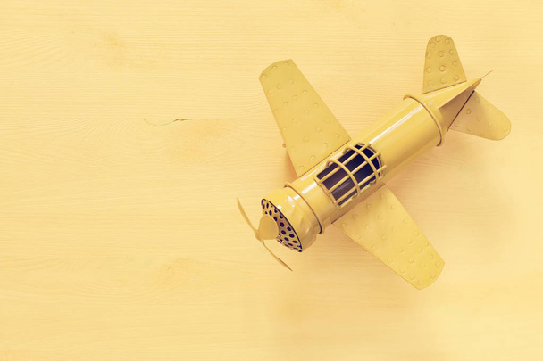 image of retro yellow metal toy airplane over wooden table - Photo, Image