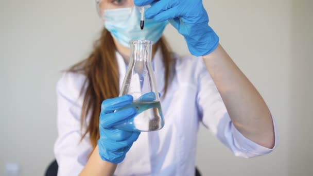 Young female chemist doing science experiment with chemicals - Materiał filmowy, wideo
