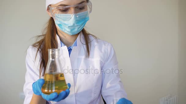 Young female chemist doing science experiment with chemicals - Materiał filmowy, wideo