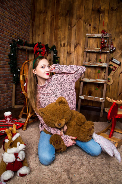 Beautiful girl sits on a background of Christmas decorations with a teddybear. Christmas and New Year concept - Фото, зображення