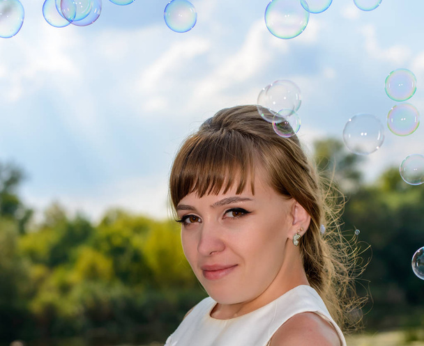 Красивая молодая невеста смотрит плавающие пузыри
 - Фото, изображение