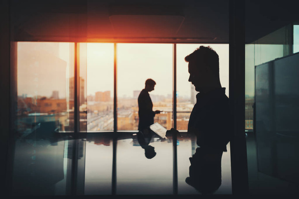 Silhouette of two businessmen in office interior - Фото, изображение