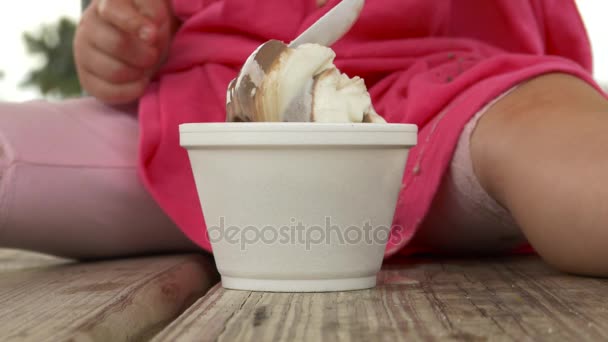 Lány rózsaszín eszik fagylaltot egy piknik asztal - Felvétel, videó