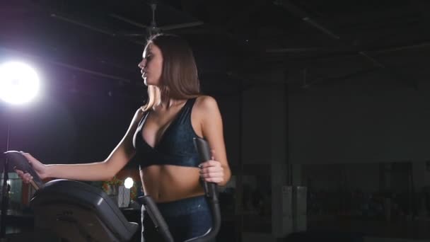 Young woman exercising on elliptical machine - Footage, Video