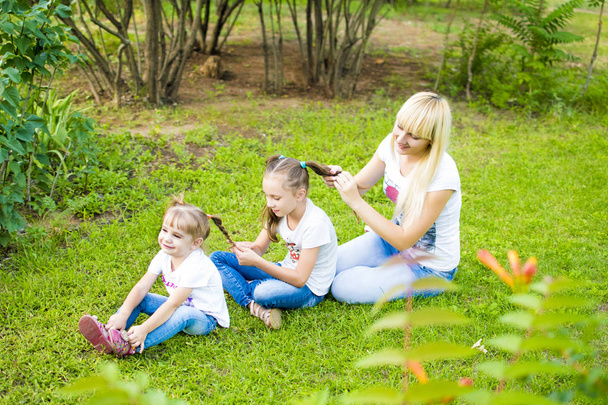 若い母親と 2 人の娘が草で遊ぶ - 写真・画像