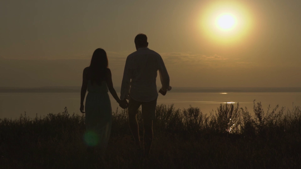 Happy couple walking on the nature near the sea on the sunset. Concept of love. - Footage, Video
