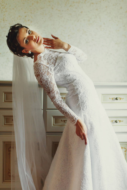 Bride bends over holding her dress delicately - 写真・画像
