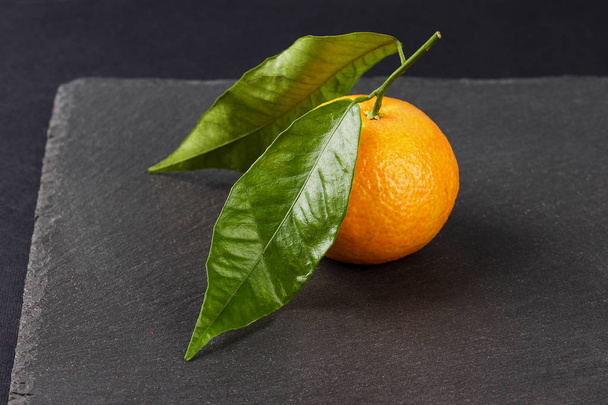 Orange mandarin on the black slate stone background - Foto, Bild