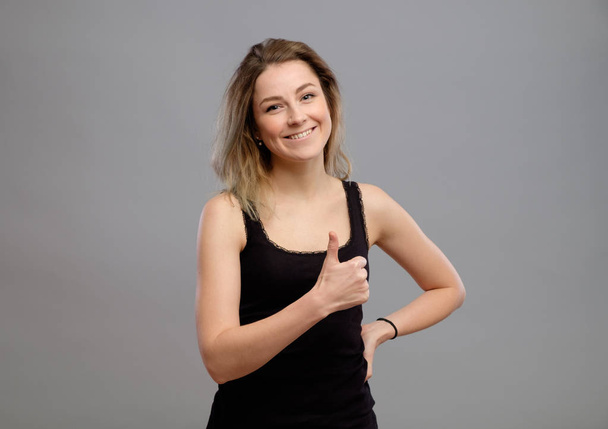 Smiling young woman showing thumbs up gesture - Фото, зображення