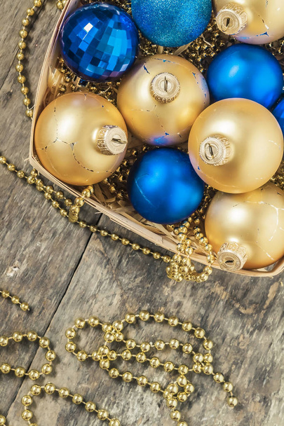 μπλε Χριστούγεννα μπάλες και το χρυσό, χάντρες βρίσκονται στην κορυφή ενός ξύλινο καλάθι  - Φωτογραφία, εικόνα