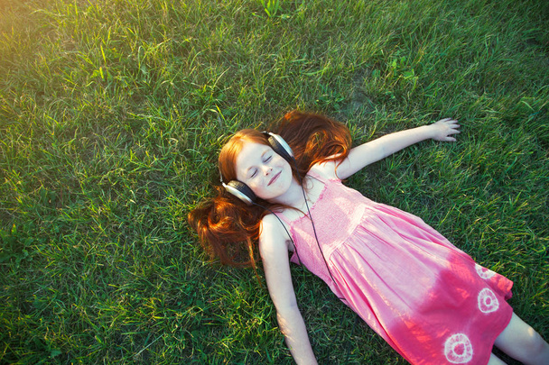 redhead girl with headphones listening to music. view from above - Photo, image