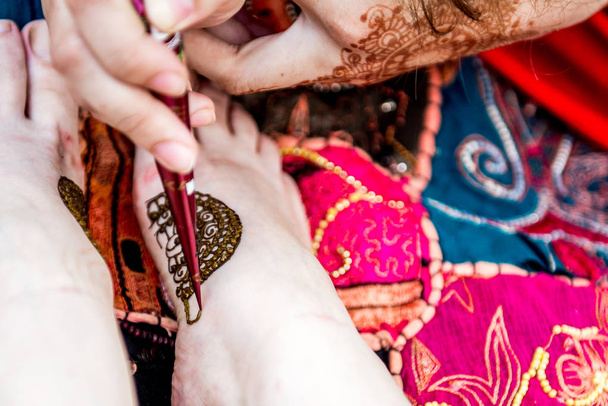 Foto de mano humana siendo decorada con tatuaje de henna, mehendi
 - Foto, imagen