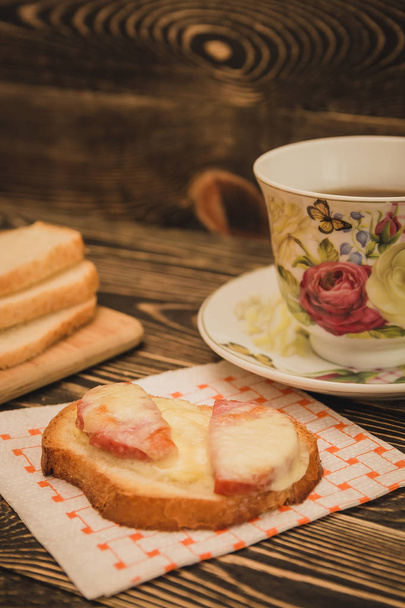 Open sandwich and cup of tea on wooden table - 写真・画像