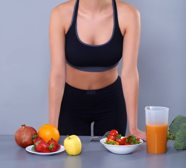 Young and beautiful woman standing near desk with vegetables - Φωτογραφία, εικόνα