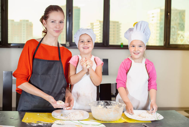 Two lovely children together with mother preparing a cake - Fotoğraf, Görsel