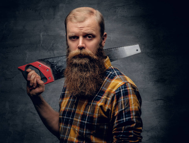 Bearded carpenter man holding handsaw. - Photo, Image