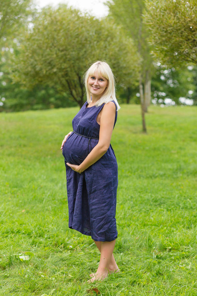 Νεαρή έγκυος γυναίκα ανάπαυσης σε ένα πάρκο - Φωτογραφία, εικόνα