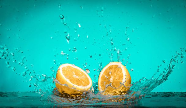 Лимонные ломтики падают на воду с большим всплеском на голубой бэкгро
 - Фото, изображение