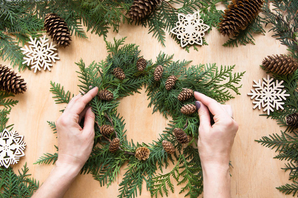 Preparation for Christmas holiday. Christmas composition of wreath, decor, dry orange, twigs and snowflakes. Woman prepare a wreath. Top view and copy space. Flat lay. - Valokuva, kuva