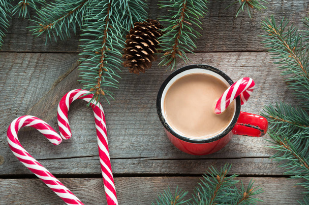Mug hot coffee with milk, red candy cane in shape of heart on the wooden background. New Year. Holiday card. Rustic style. Top view and copy space. - Fotoğraf, Görsel