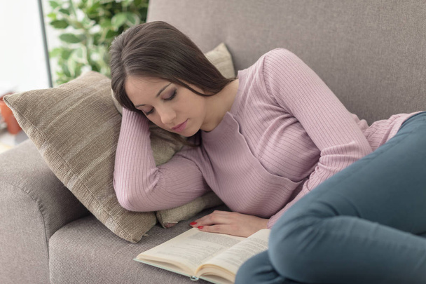 κορίτσι ξαπλωμένη στον καναπέ και διαβάζοντας ένα βιβλίο - Φωτογραφία, εικόνα
