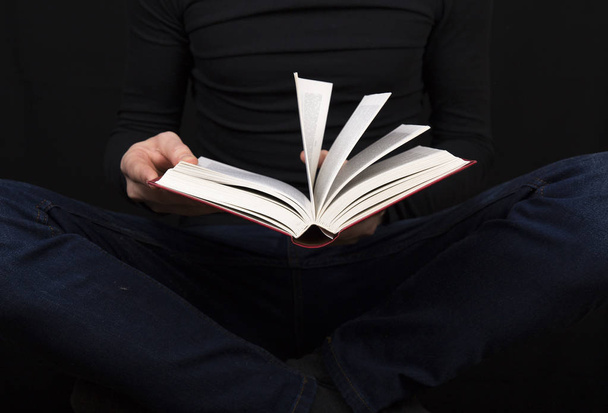 an open book in the hands of a man in a black jacket and jeans,  - Photo, Image